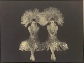 Pair of silver sequin costumes with feathered headdresses on a black background