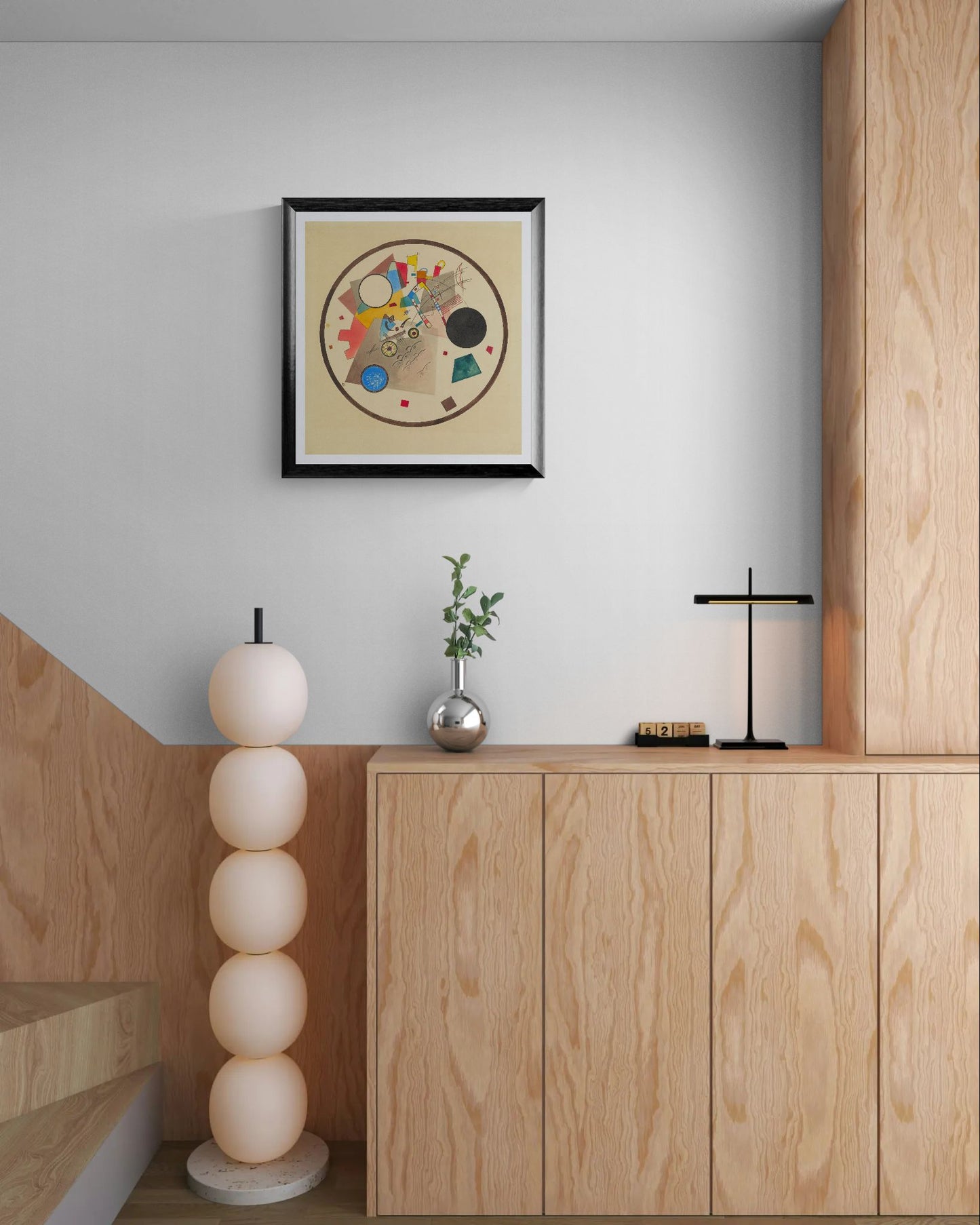 Modern interior with wooden cabinets, decorative lamp, and framed artwork on a light gray wall.