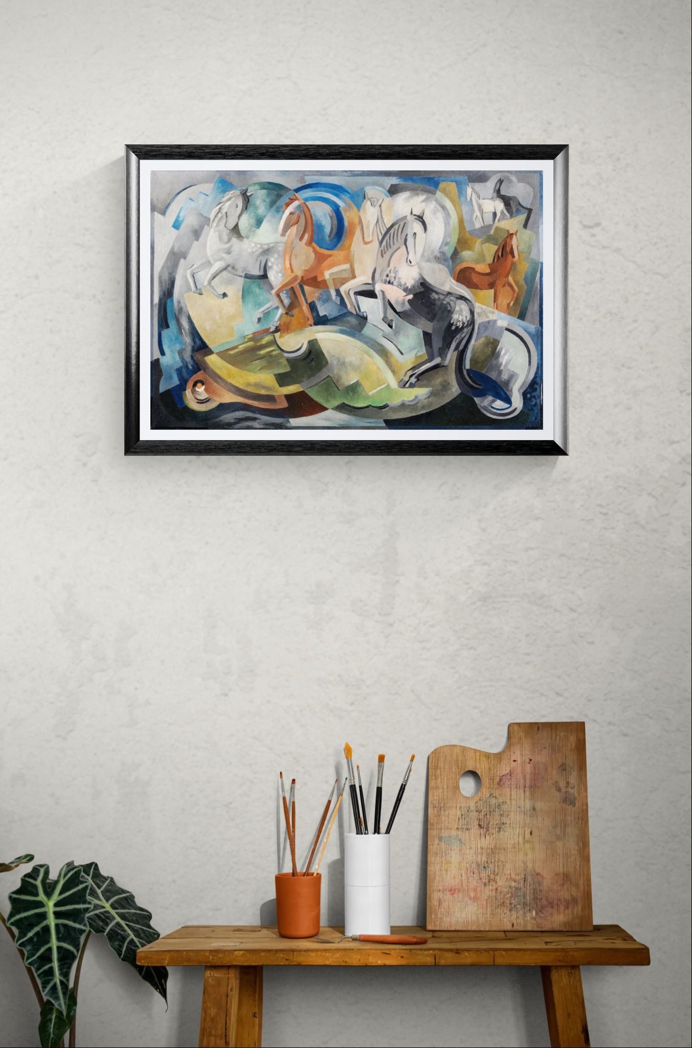 Framed abstract painting on a wall above a wooden table with art supplies.