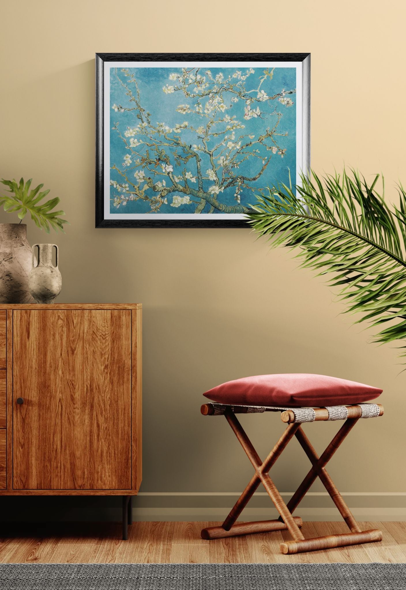 Framed artwork of floral branches on a wall above a wooden cabinet with a red cushioned stool.