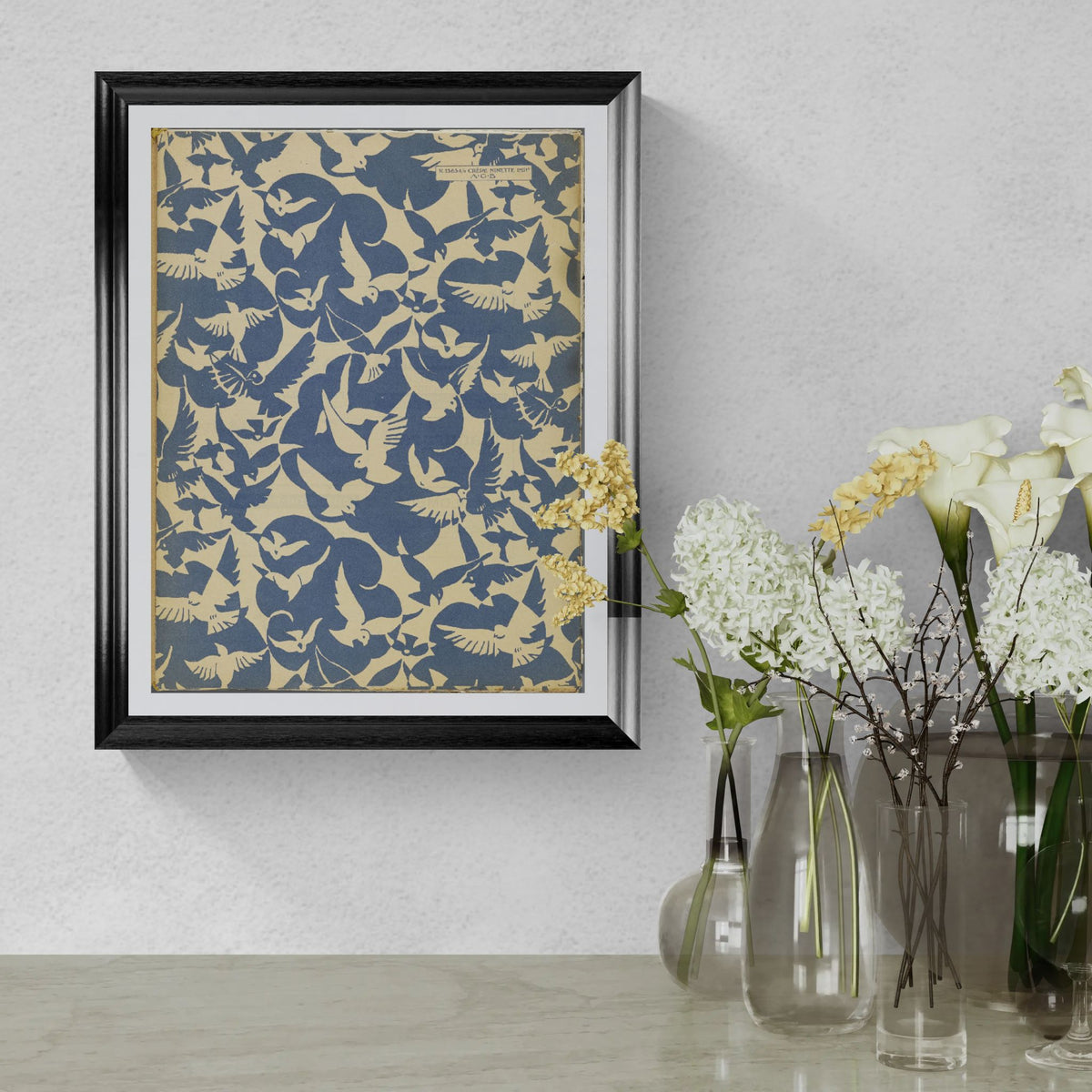 Framed abstract art piece on a wall with decorative vases and flowers below.