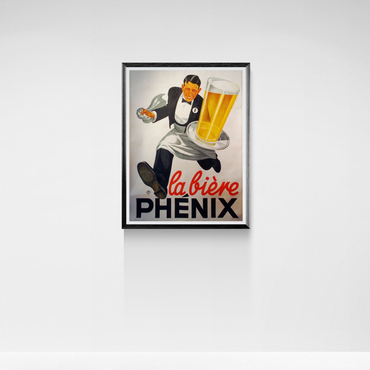 Framed vintage-style advertisement for La Bière Phénix on a white wall.