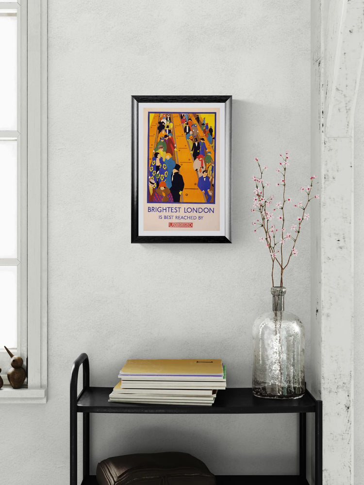 Framed poster on a wall above a black shelf with books and a vase.