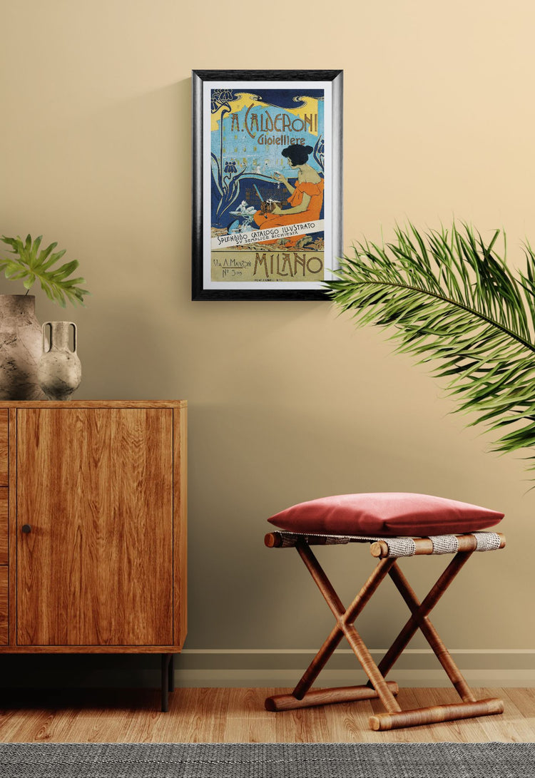 Framed poster on a wall above a wooden cabinet and red stool with a plant in the foreground.