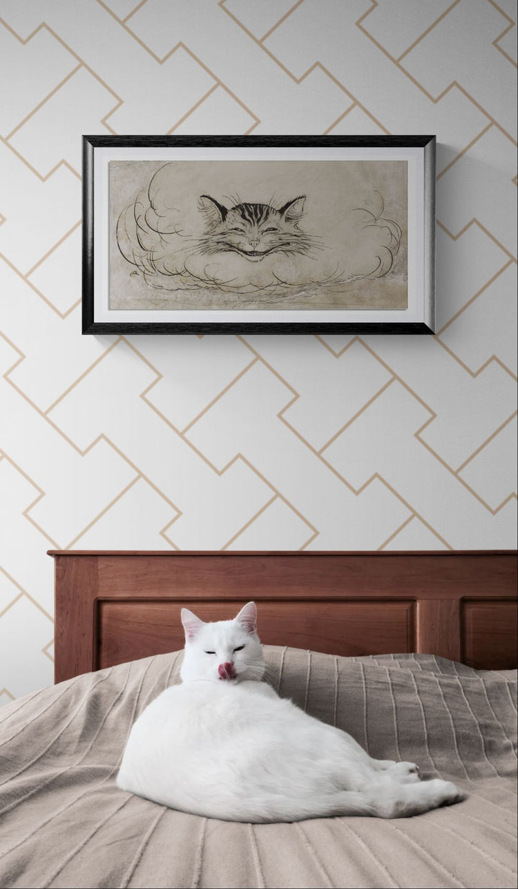 White cat sitting on a bed with a framed black and white drawing of a cat on the wall above.