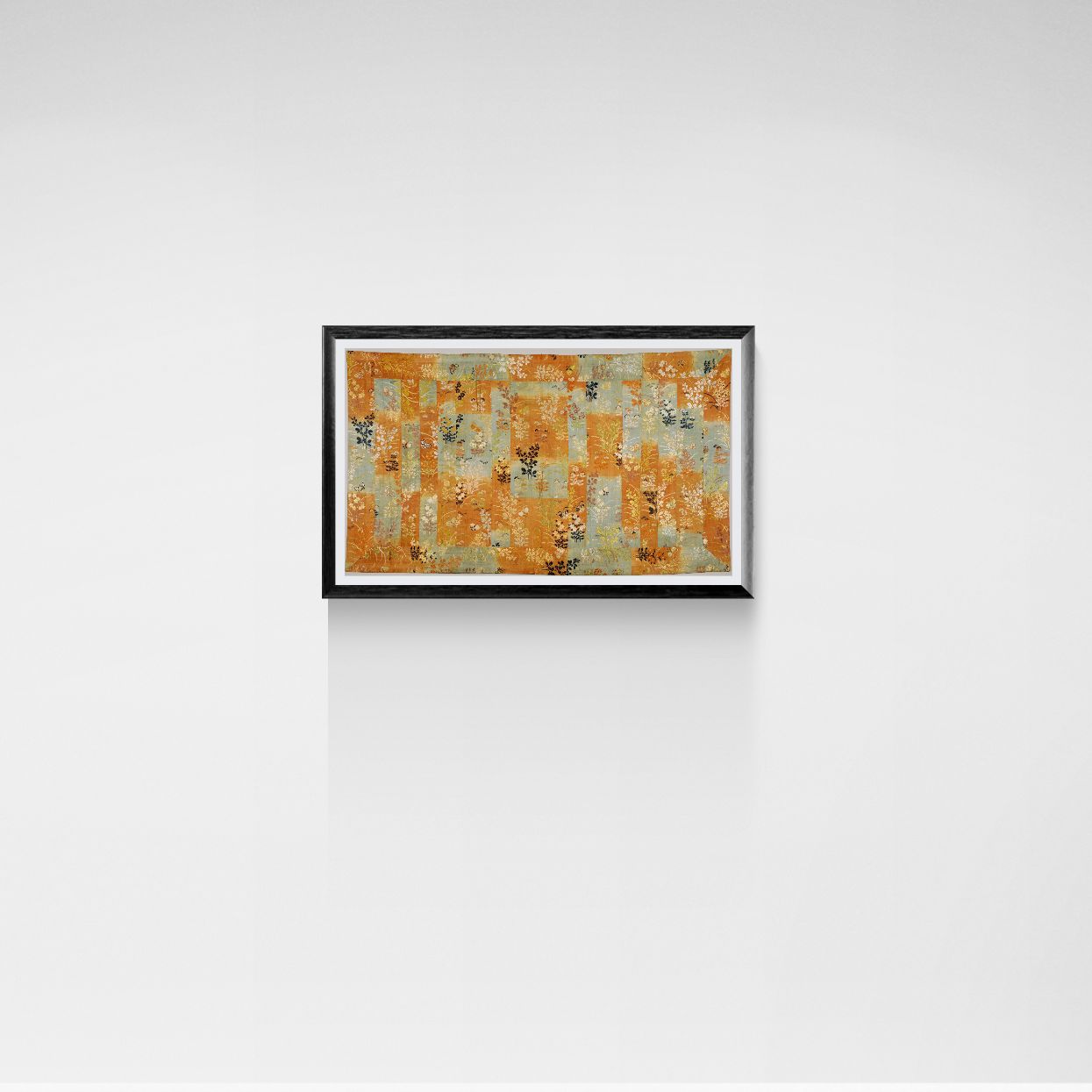 Framed abstract artwork with orange and brown tones on a white wall