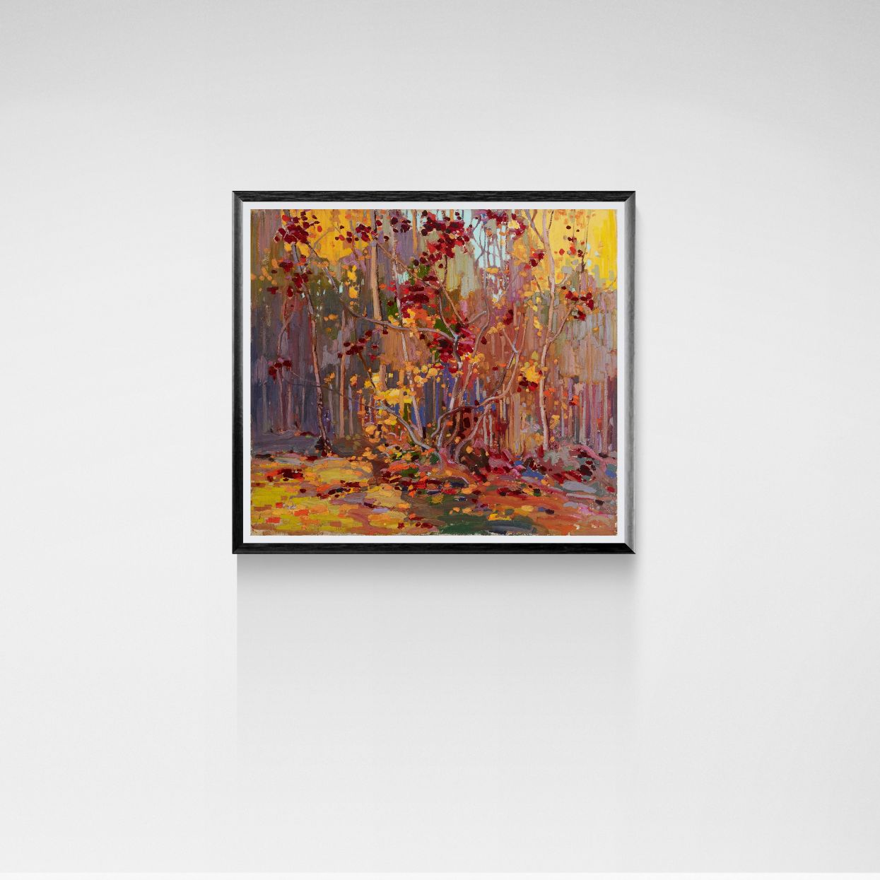 Framed painting of a forest scene with autumn colors on a white wall.