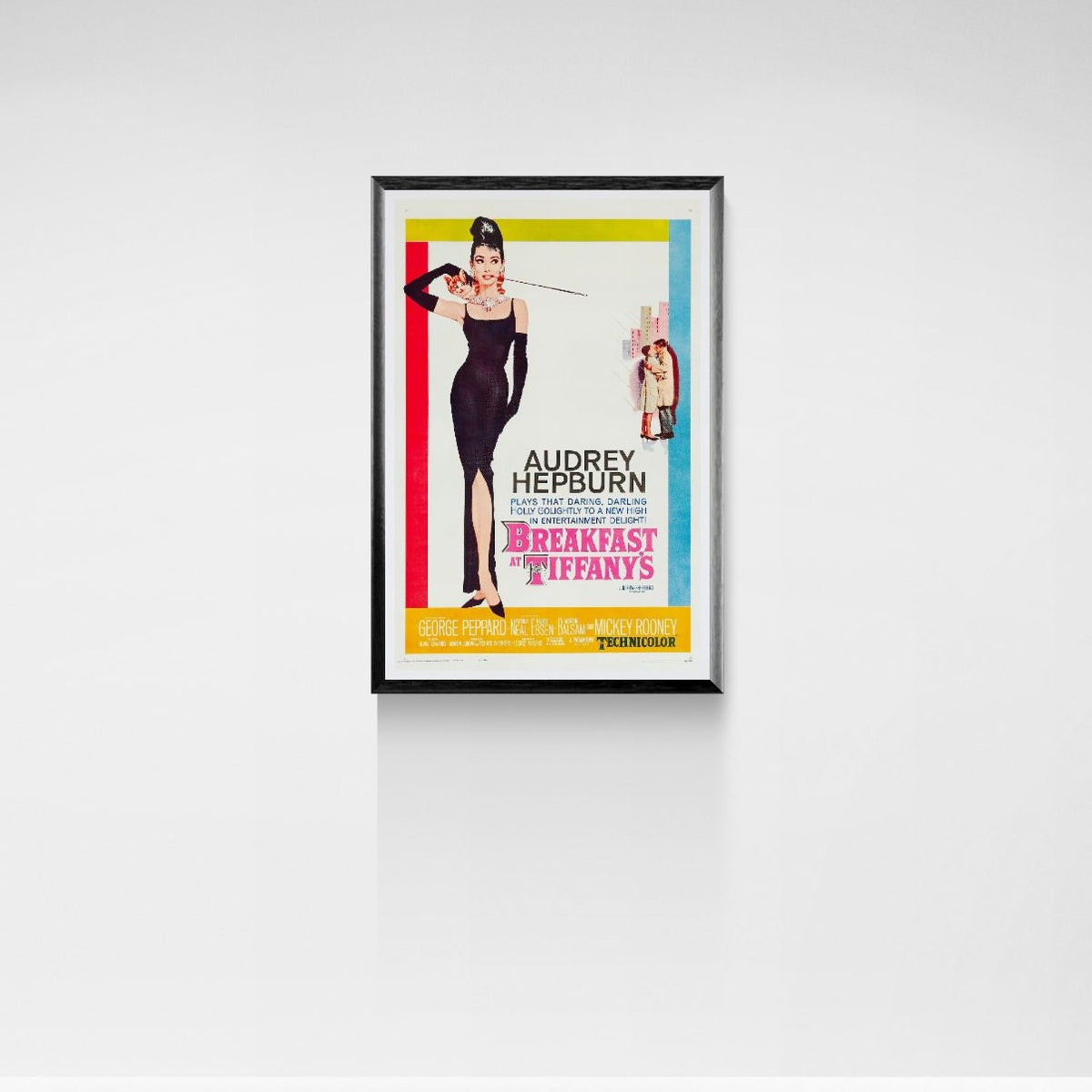 Framed movie poster of Audrey Hepburn from 'Breakfast at Tiffany's' on a white wall.