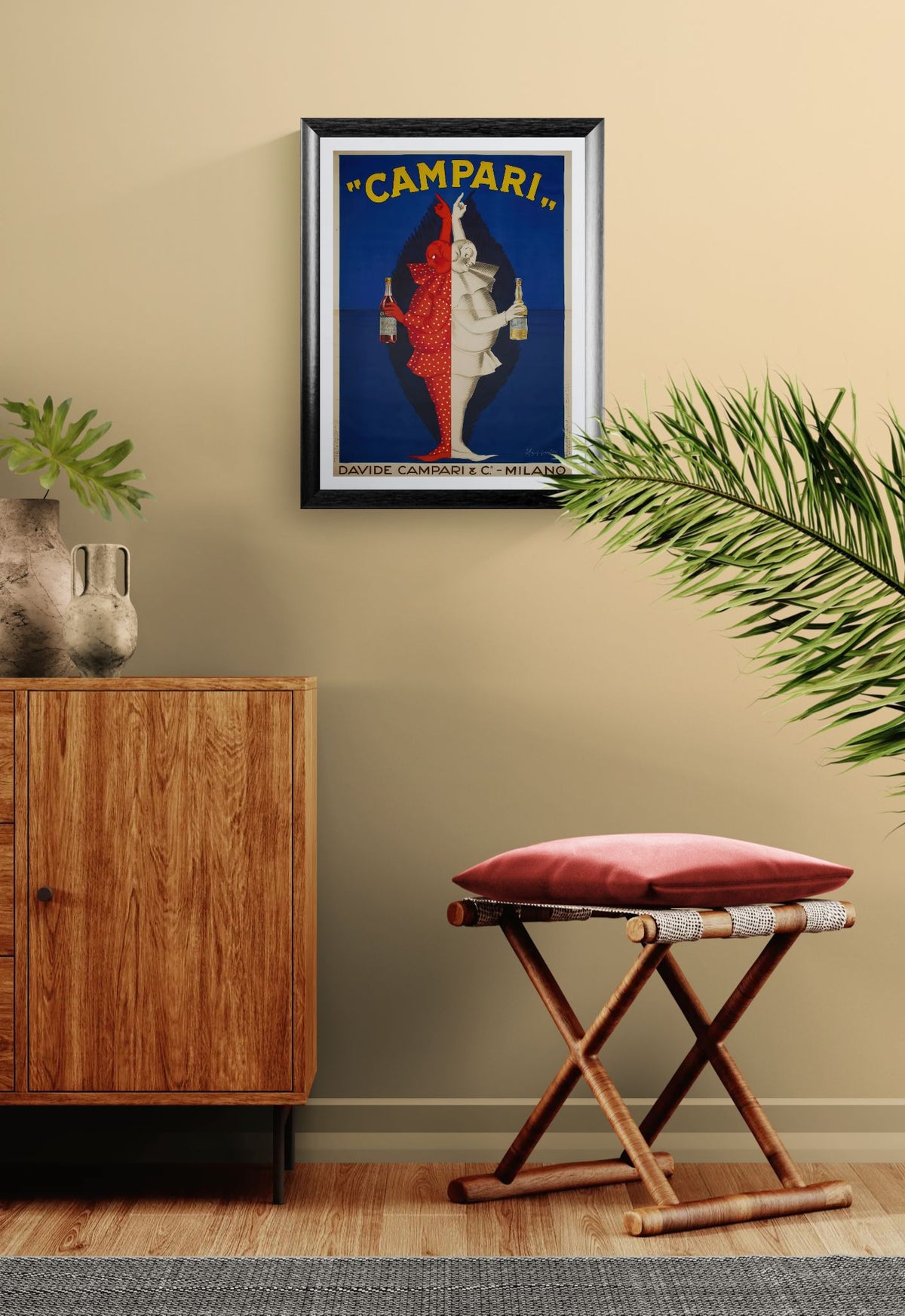 Framed Campari print advertisement on a wall with wooden cabinet and stool in the foreground.
