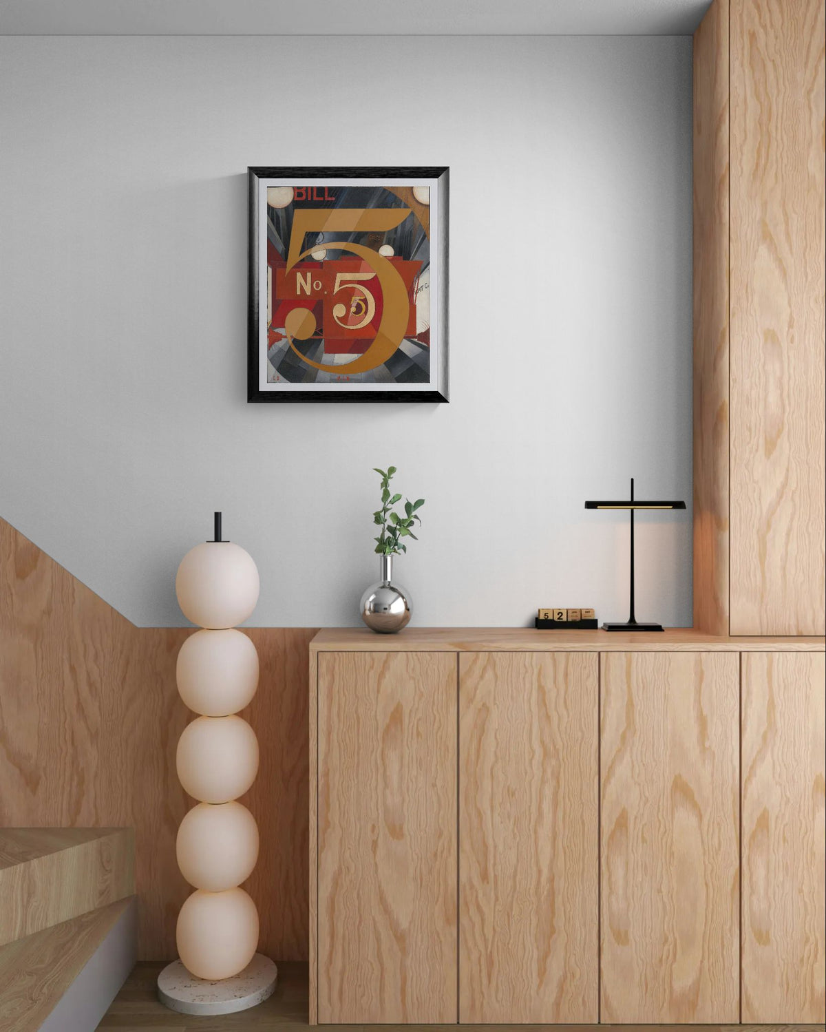 Modern interior with wooden cabinets, decorative lamp, and framed artwork on a light gray wall.