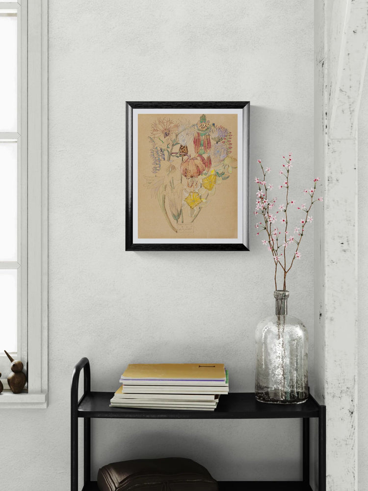 Framed artwork on a wall above a black shelf with books and a vase.
