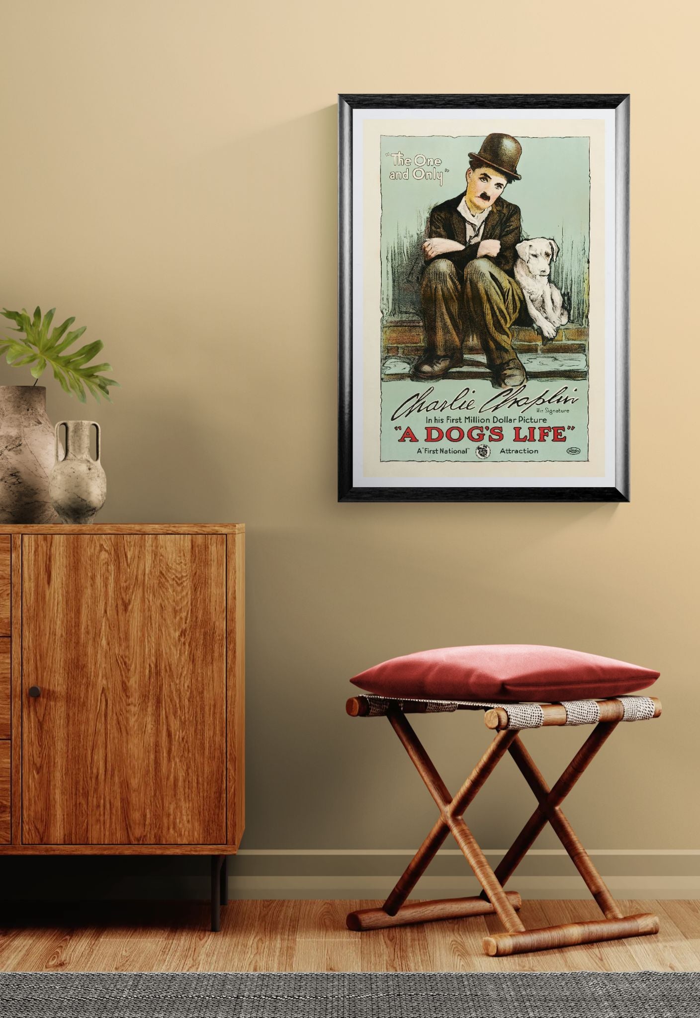 Framed movie poster of Charlie Chaplin and a dog on a wall above a wooden cabinet and stool.