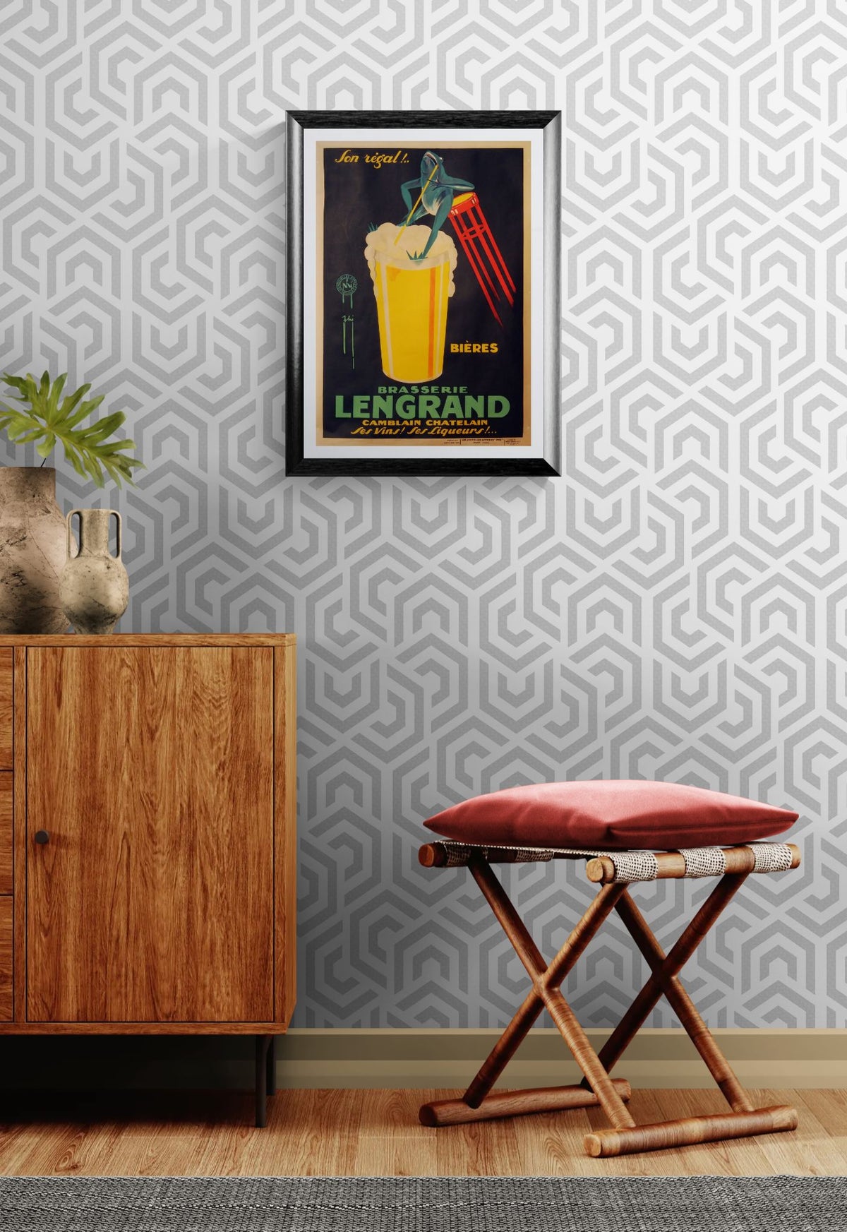 Framed poster on a wall with geometric pattern, wooden cabinet, and red stool.