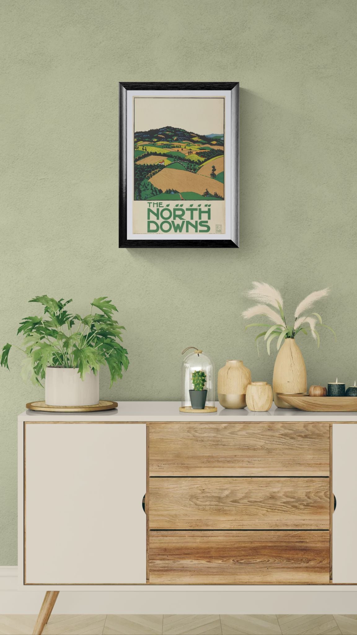 Framed artwork on a wall above a wooden cabinet with decorative items.