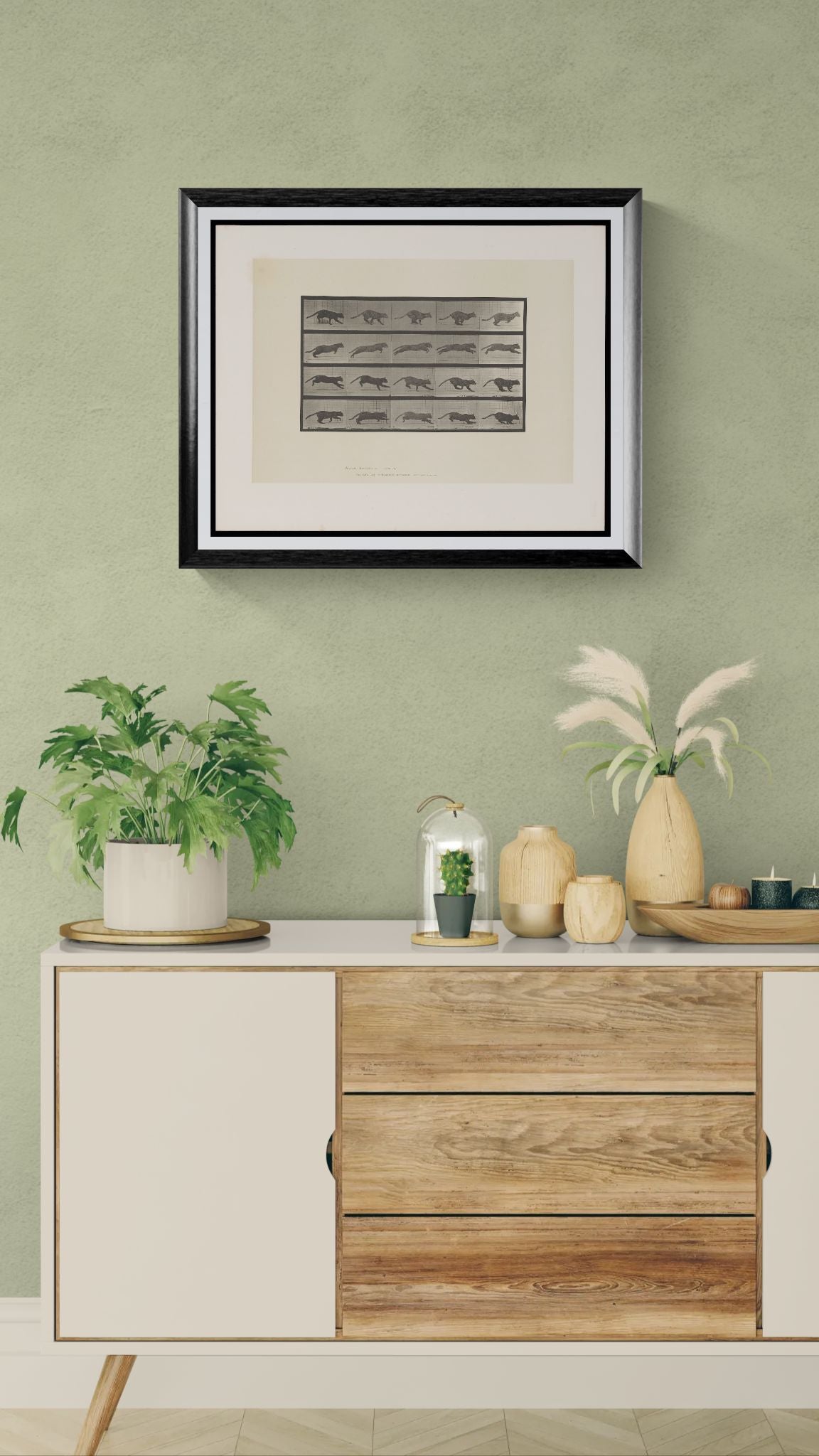 Framed artwork above a wooden cabinet with decorative items against a green wall.