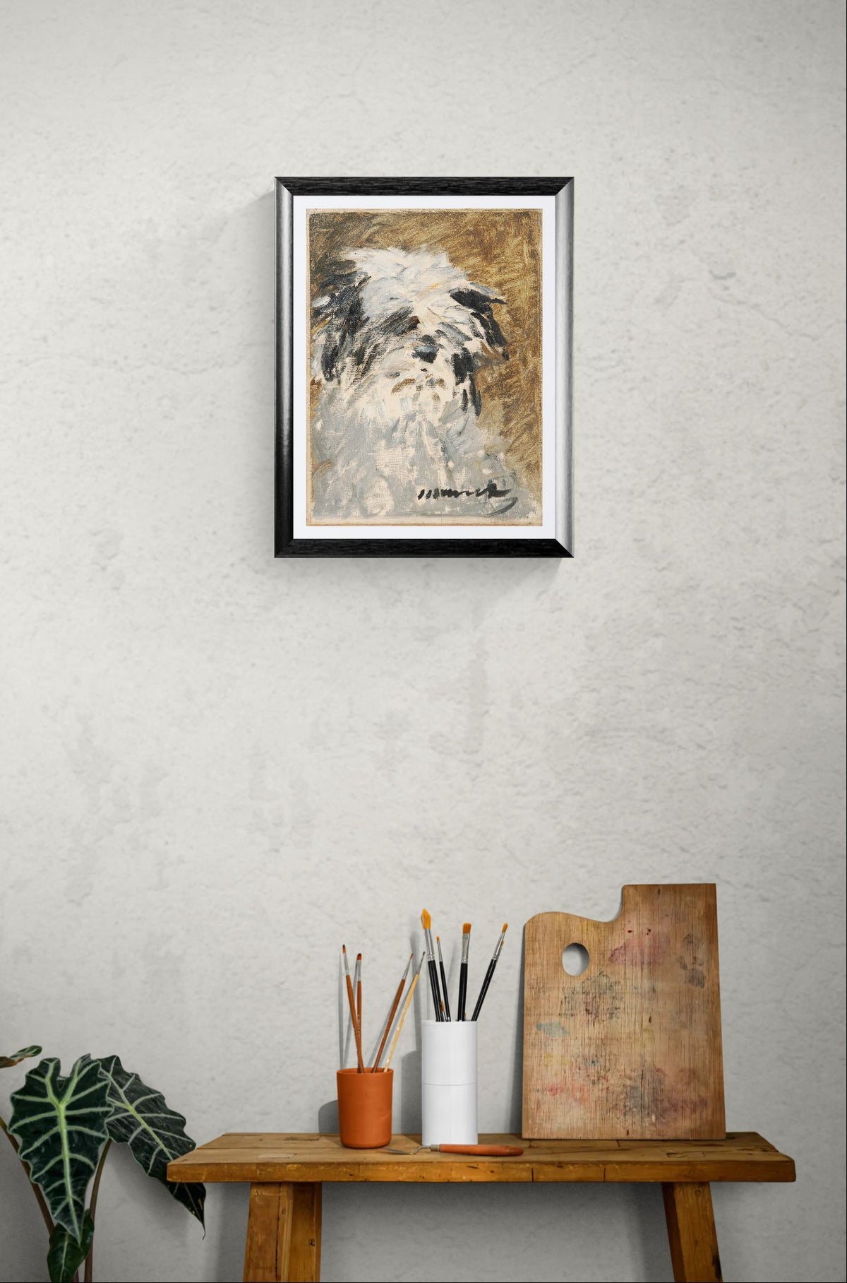 Framed artwork of a dog on a wall above a wooden table with art supplies.