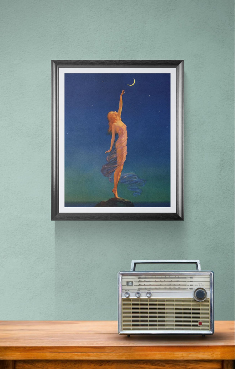 Framed artwork of a woman reaching for the moon above a vintage radio on a wooden surface.