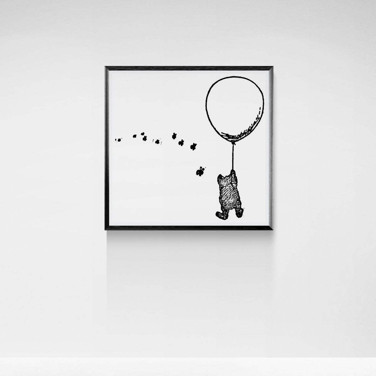 Framed black and white illustration of a bear with a balloon on a white wall.