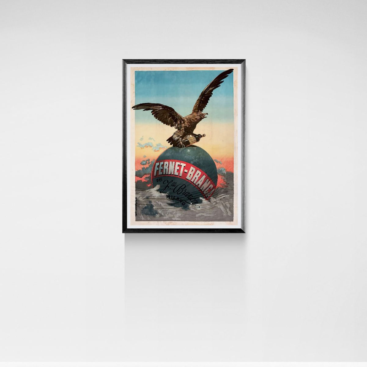 Framed artwork of an eagle on a globe with 'Fernet-Brand' text against a white wall.