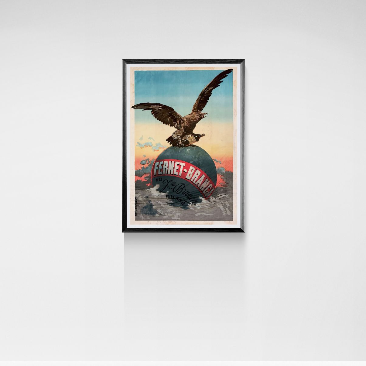 Framed artwork of an eagle on a globe with 'Fernet-Brand' text against a white wall.