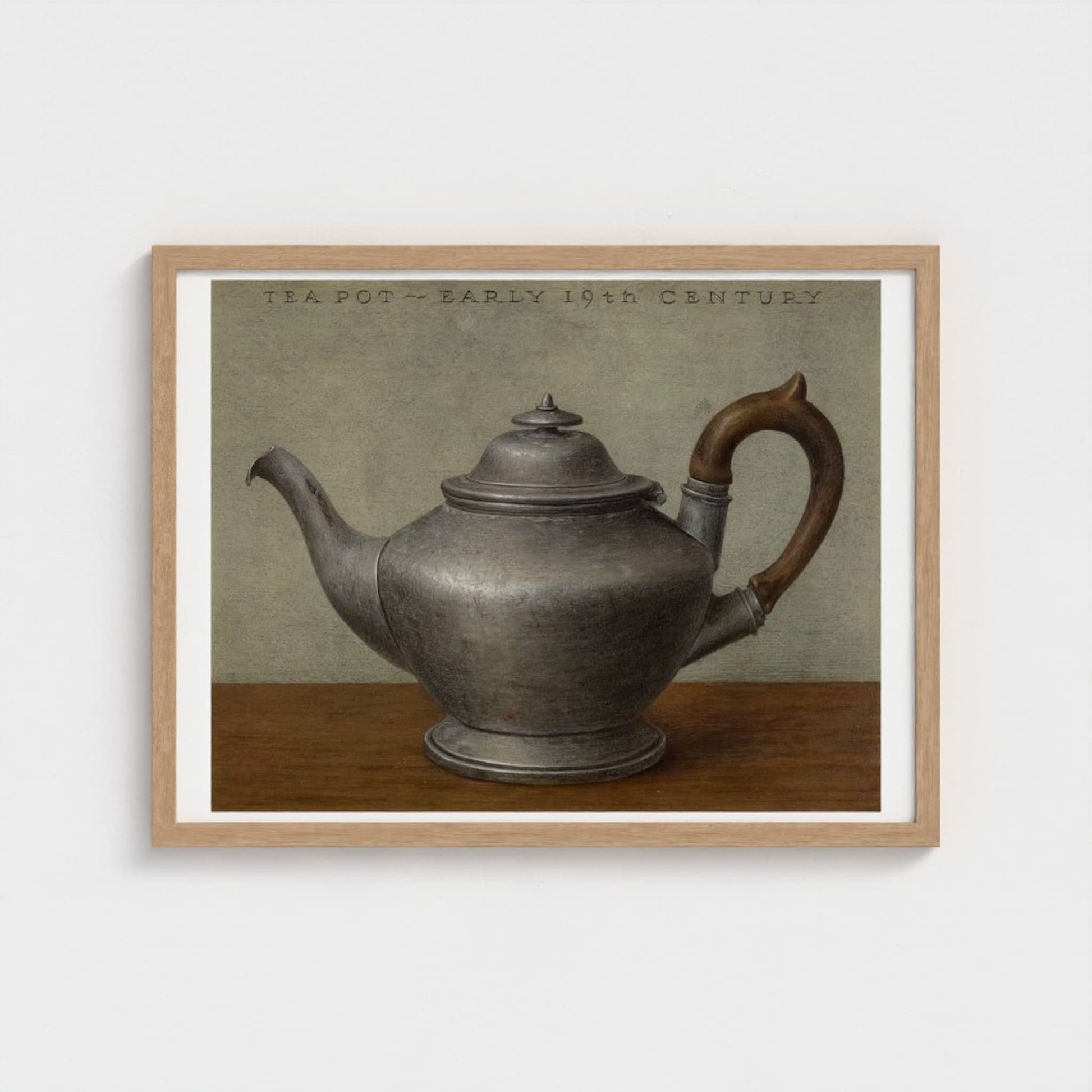 Framed artwork of a silver teapot on a wooden surface with a neutral background