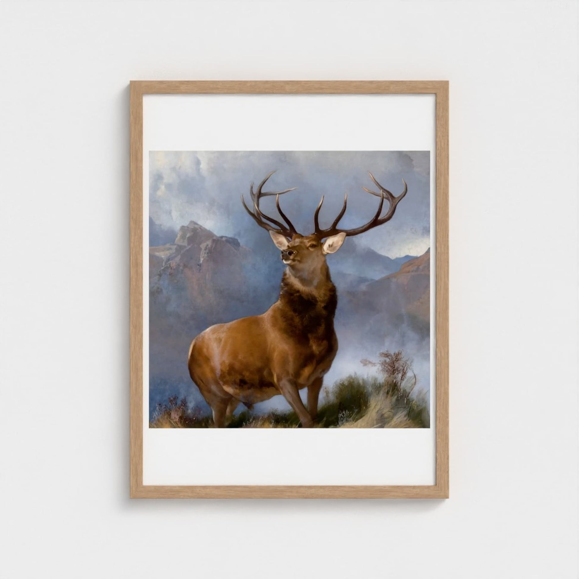 Framed artwork of a deer with mountains in the background on a white wall.