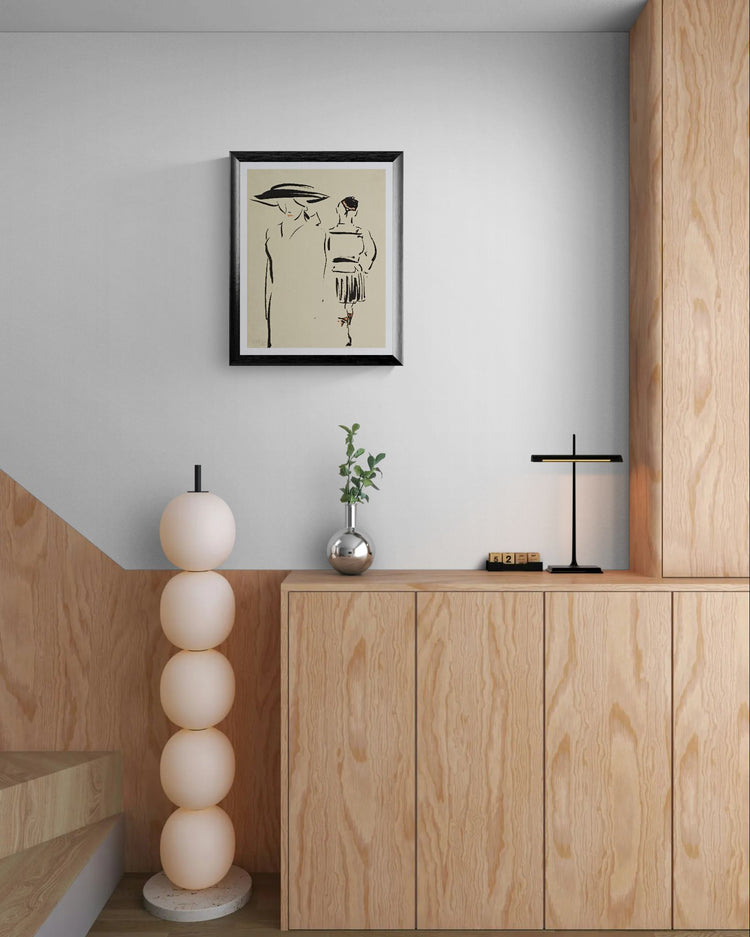 Modern interior with wooden cabinets, decorative lamp, and framed artwork on a light gray wall.