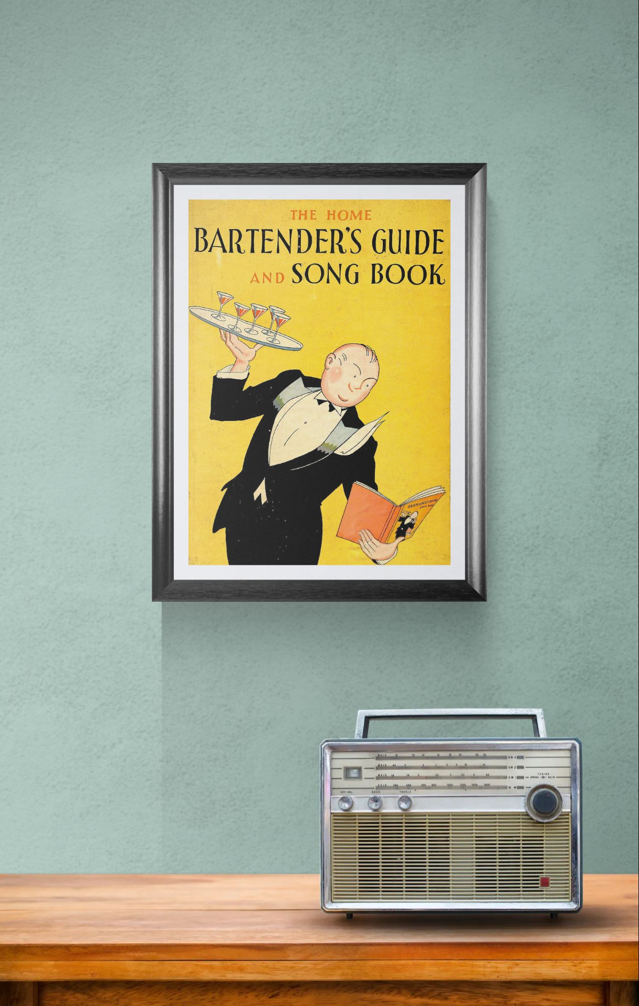 Framed poster of 'The Home Bartender's Guide and Song Book' on a wall with a vintage radio below.