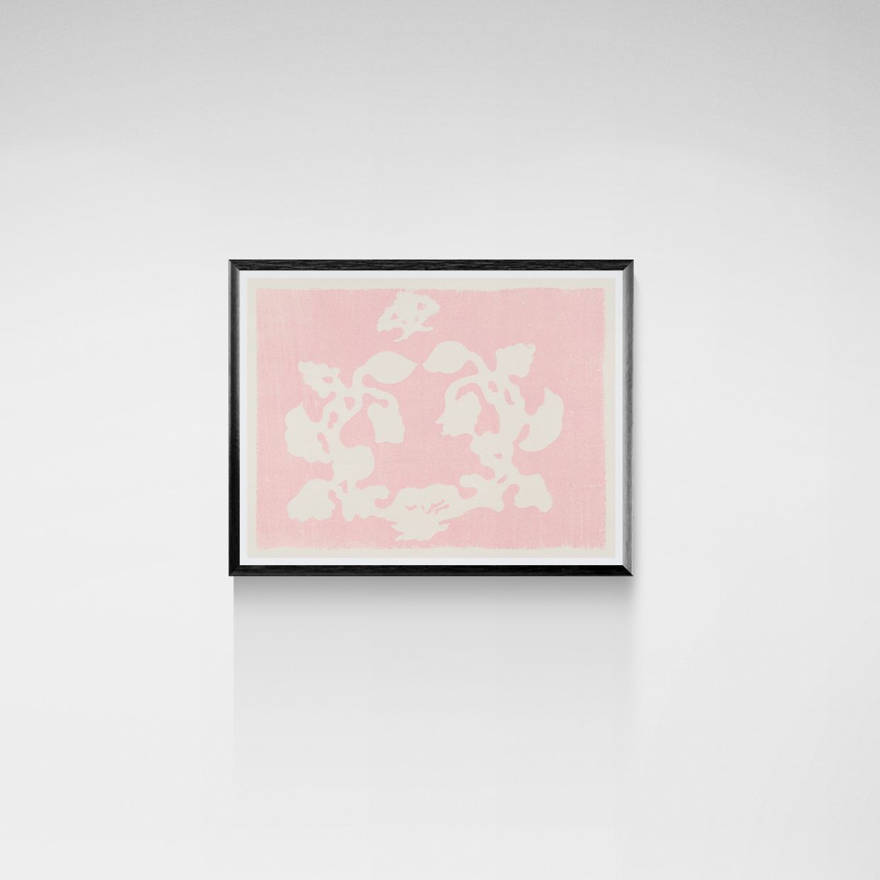 Framed artwork with white floral pattern on a pink background against a white wall