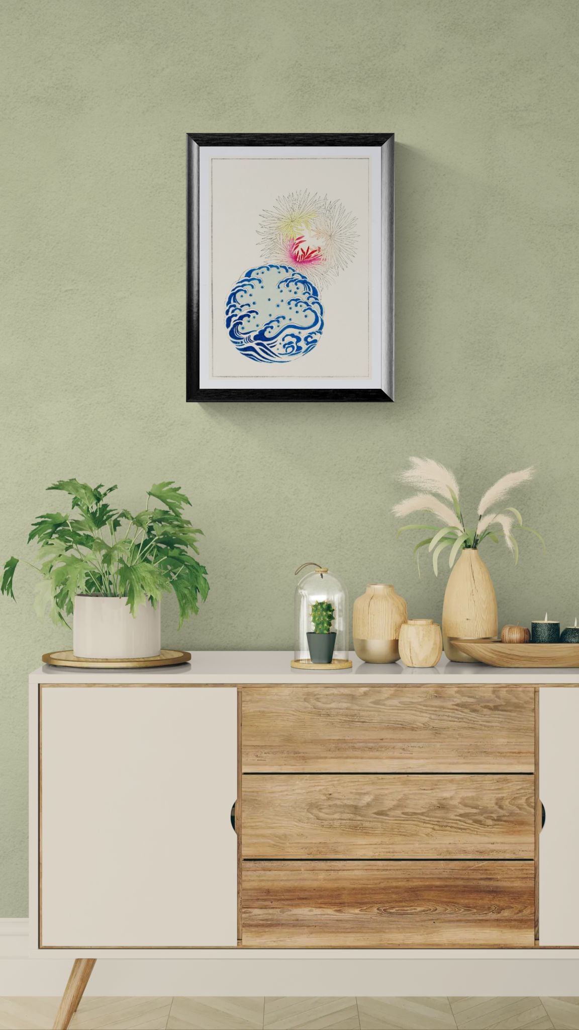 Decorative setup with a framed artwork, plants, and vases on a wooden cabinet against a green wall.