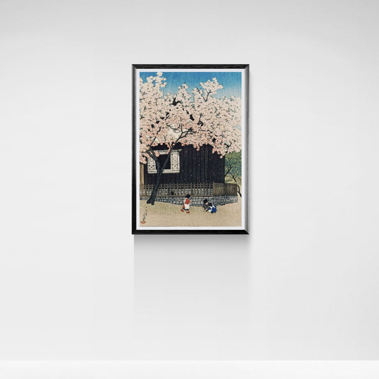 Framed artwork of cherry blossoms with a traditional Japanese building in the background on a white wall.