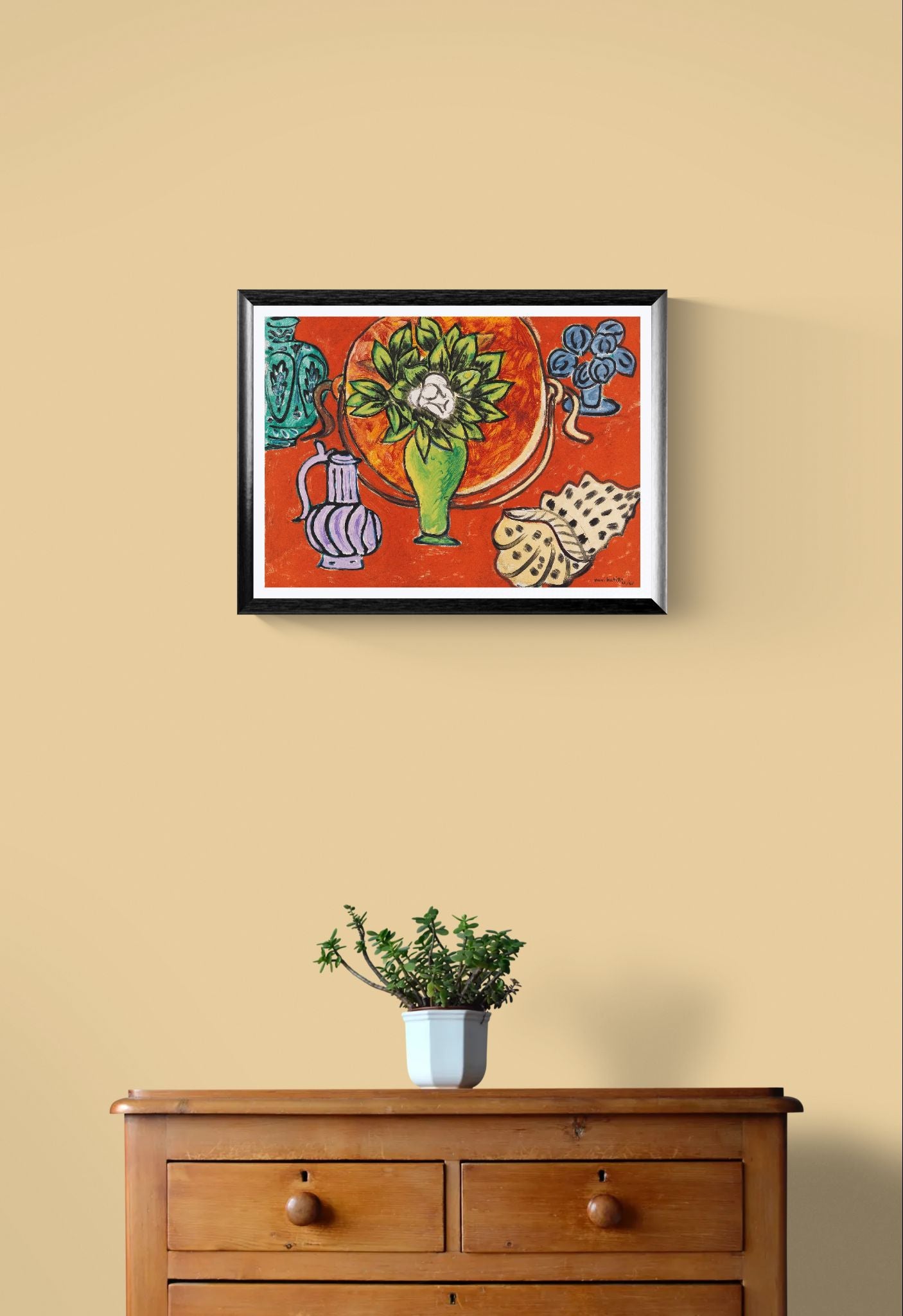 Framed colorful artwork on a beige wall above a wooden dresser with a plant.