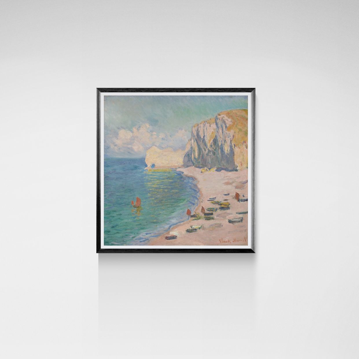 Framed painting of a beach scene with boats and cliffs on a white wall.