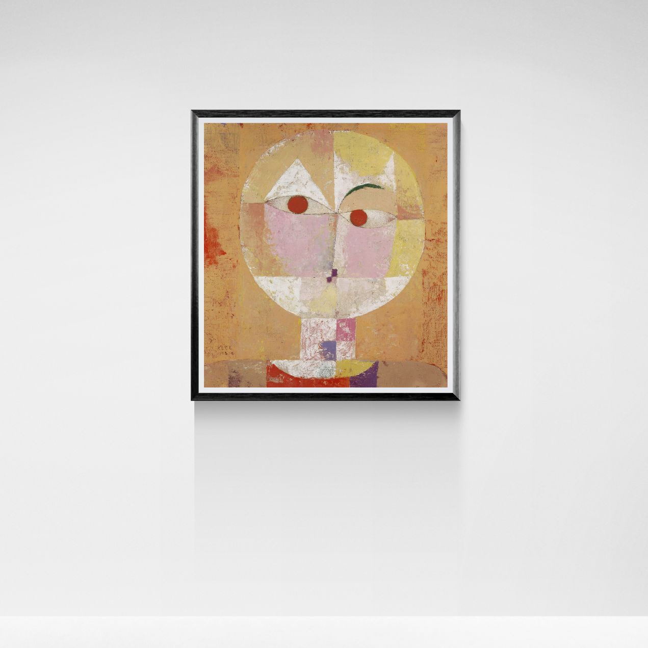 Framed abstract artwork with a stylized face on a white wall