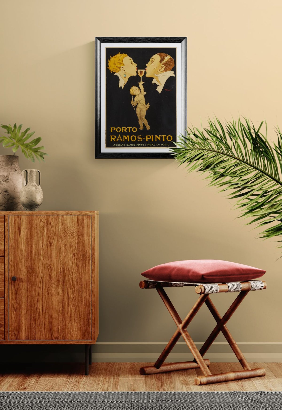 Framed vintage poster on a wall with a wooden cabinet and red stool below.