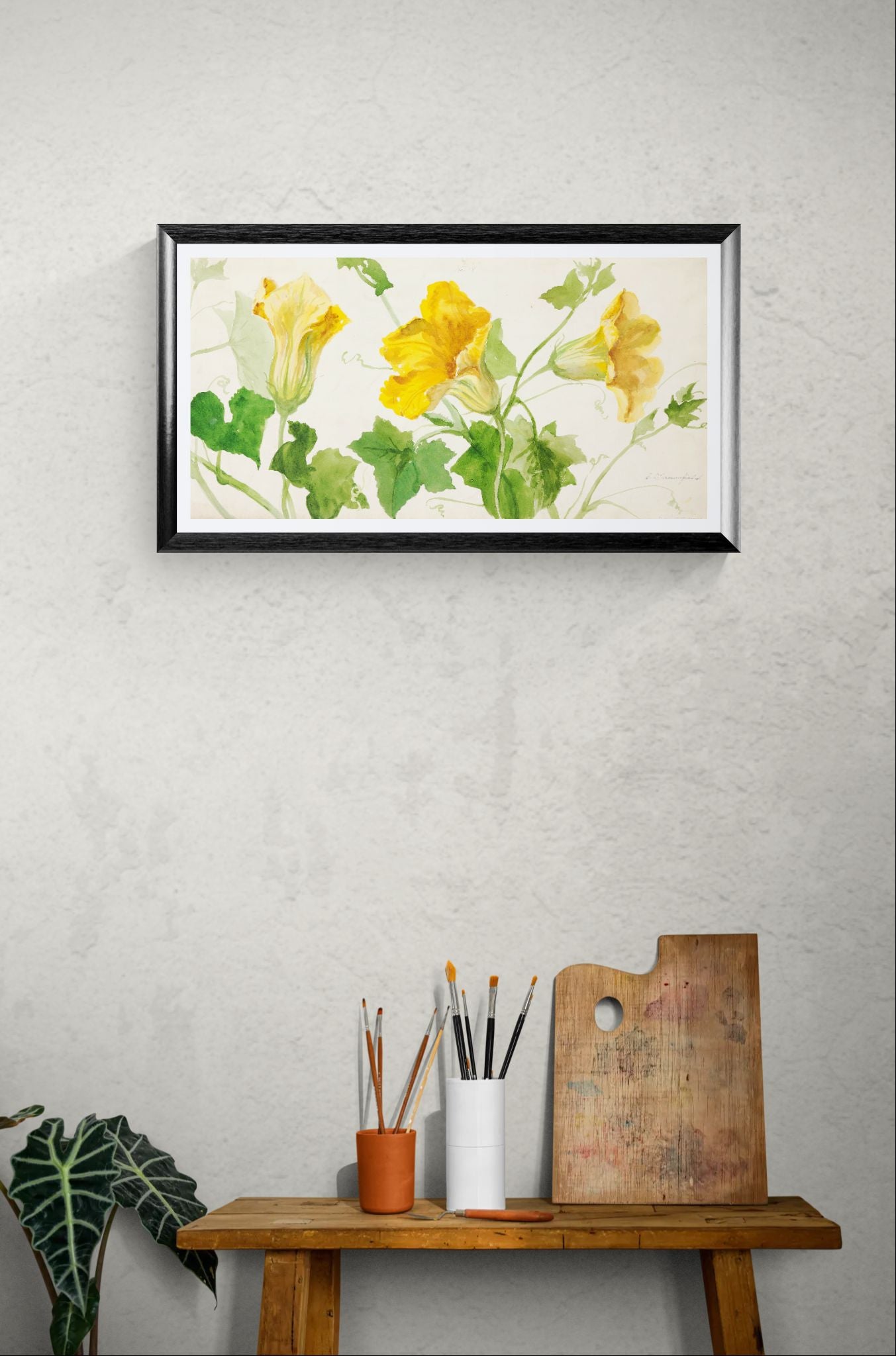 Framed floral artwork on a wall above a wooden table with art supplies.
