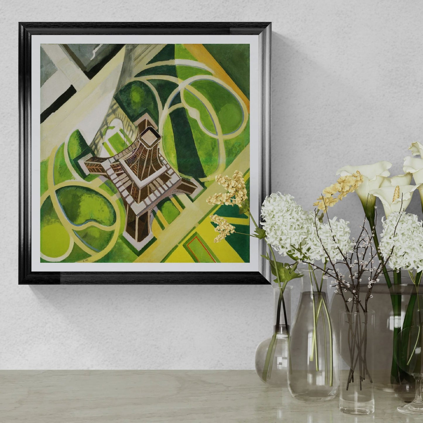 Framed abstract art piece on a wall with decorative vases and flowers below.