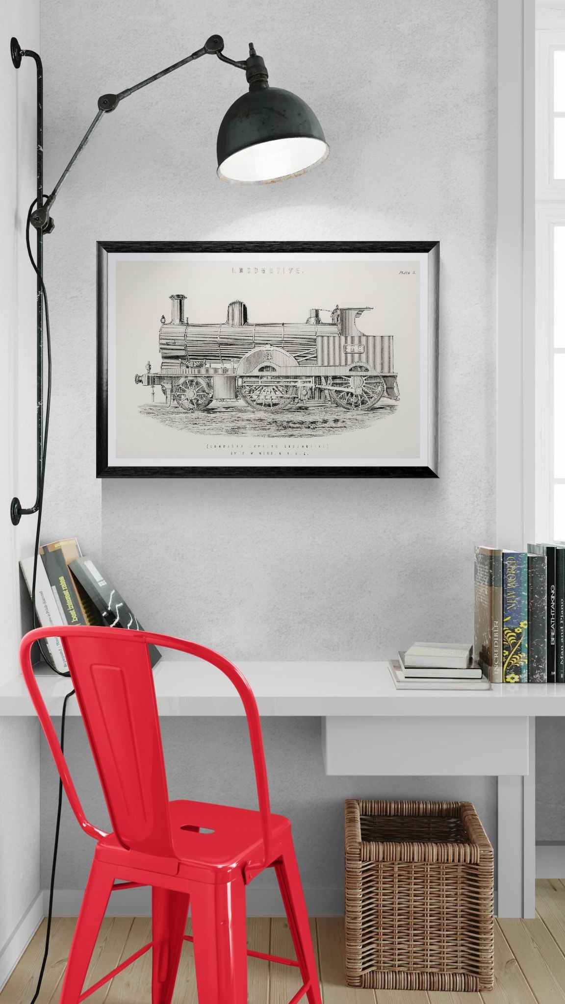 Red chair in front of a white desk with a framed black and white train illustration on the wall.