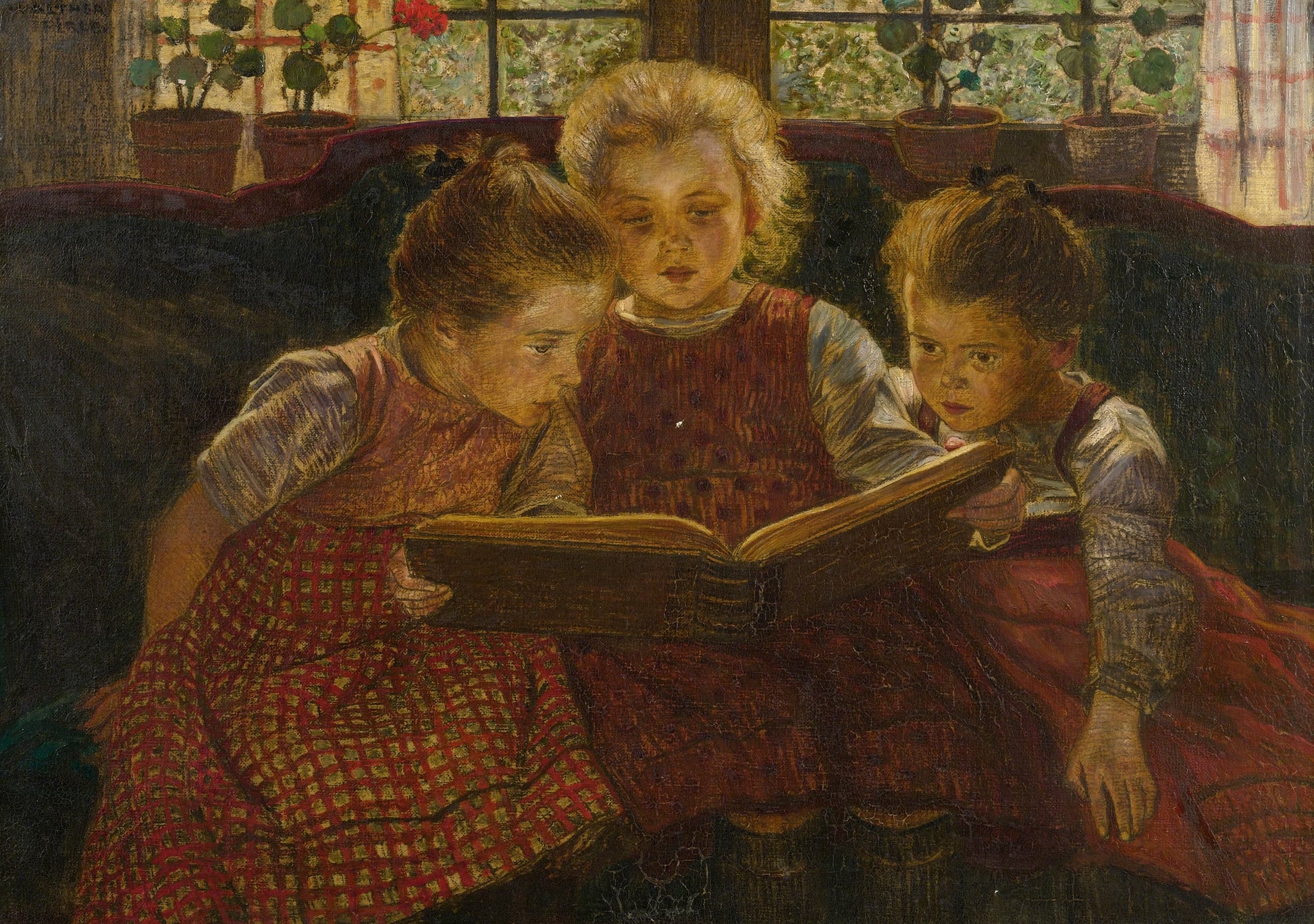 Three children in red checkered dresses reading a book together.