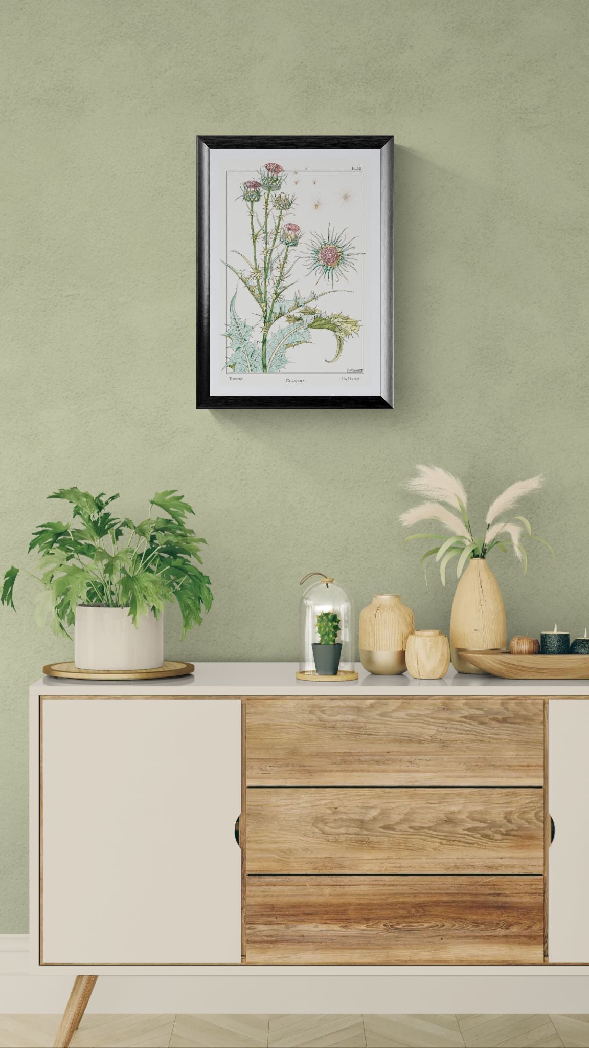 Decorative setup with a framed botanical print, plants, and a wooden cabinet against a green wall.