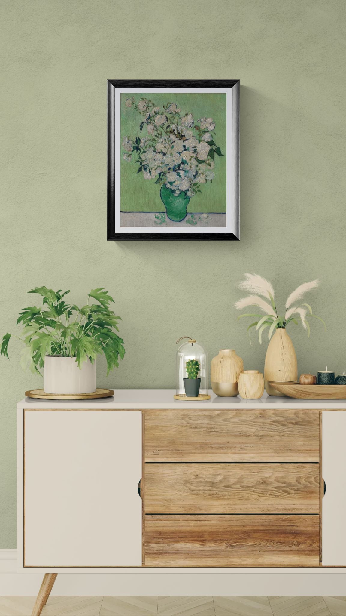 Framed artwork of a floral arrangement on a green wall above a wooden cabinet with decorative items.