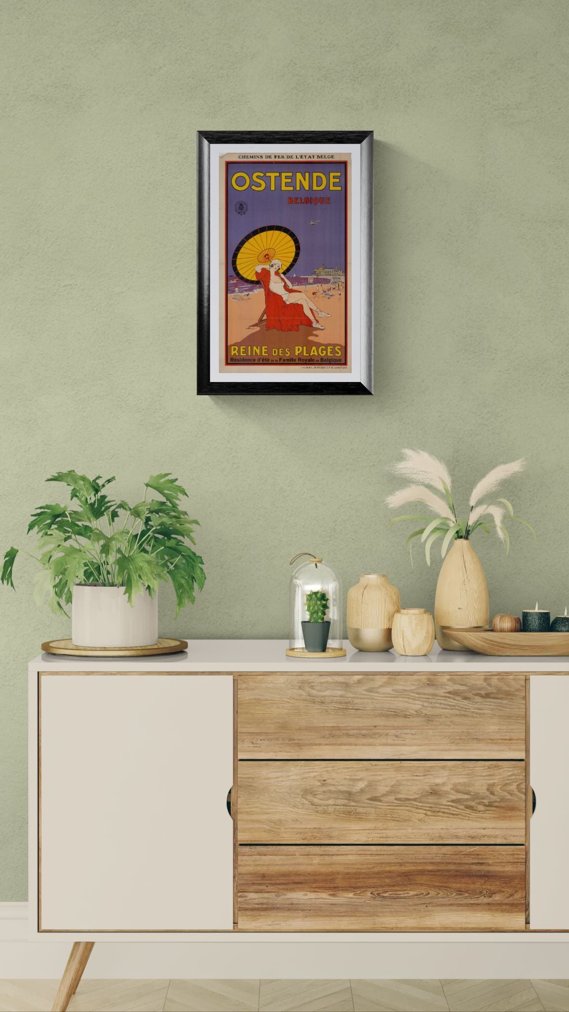 Framed vintage-style travel poster on a wall above a wooden cabinet with decorative items.