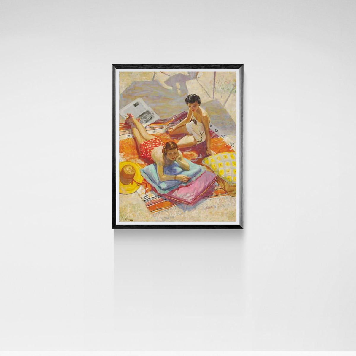 Framed artwork of a beach scene with two women on towels.