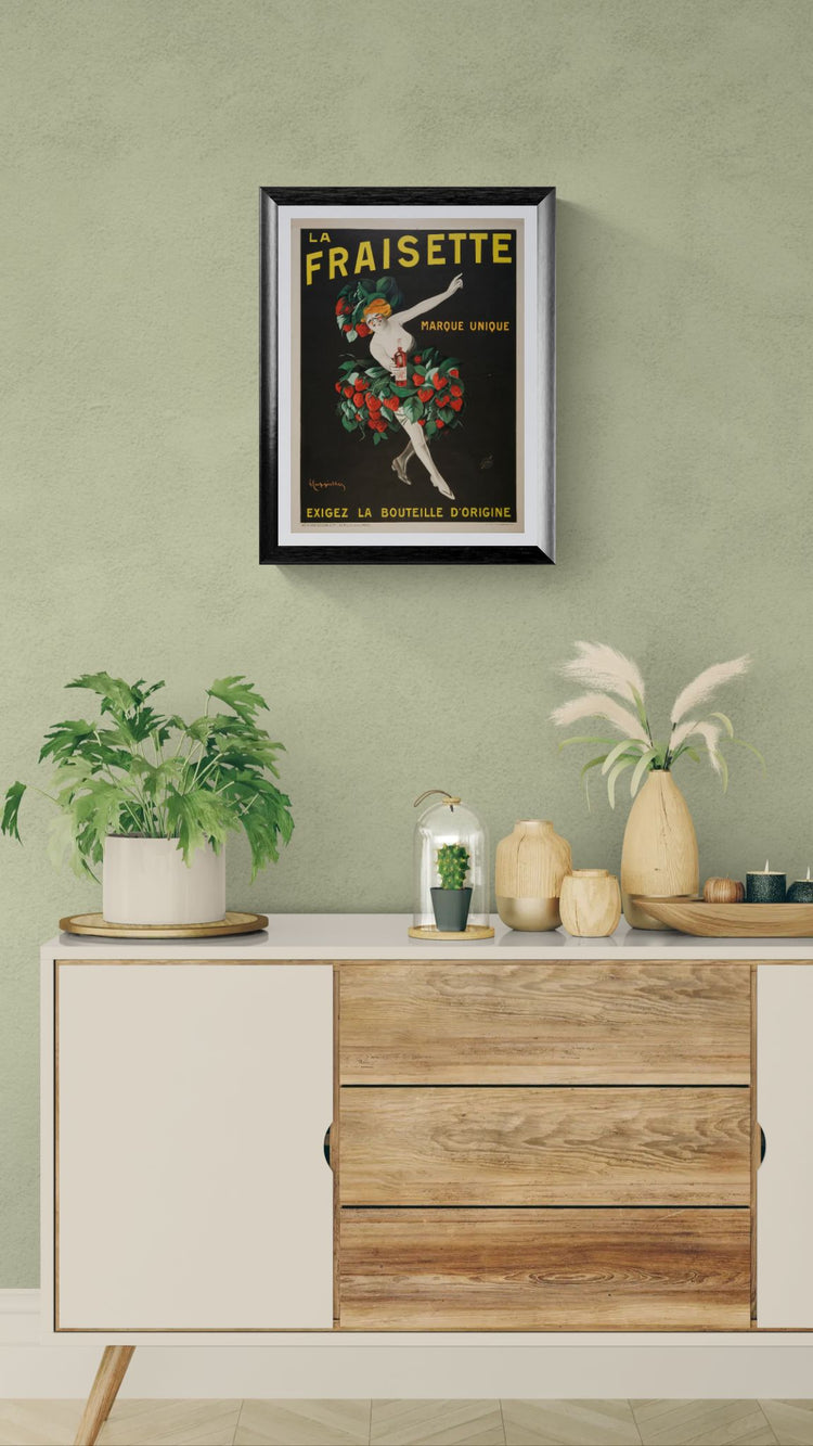 Framed vintage-style poster on a wall above a wooden cabinet with decorative items.