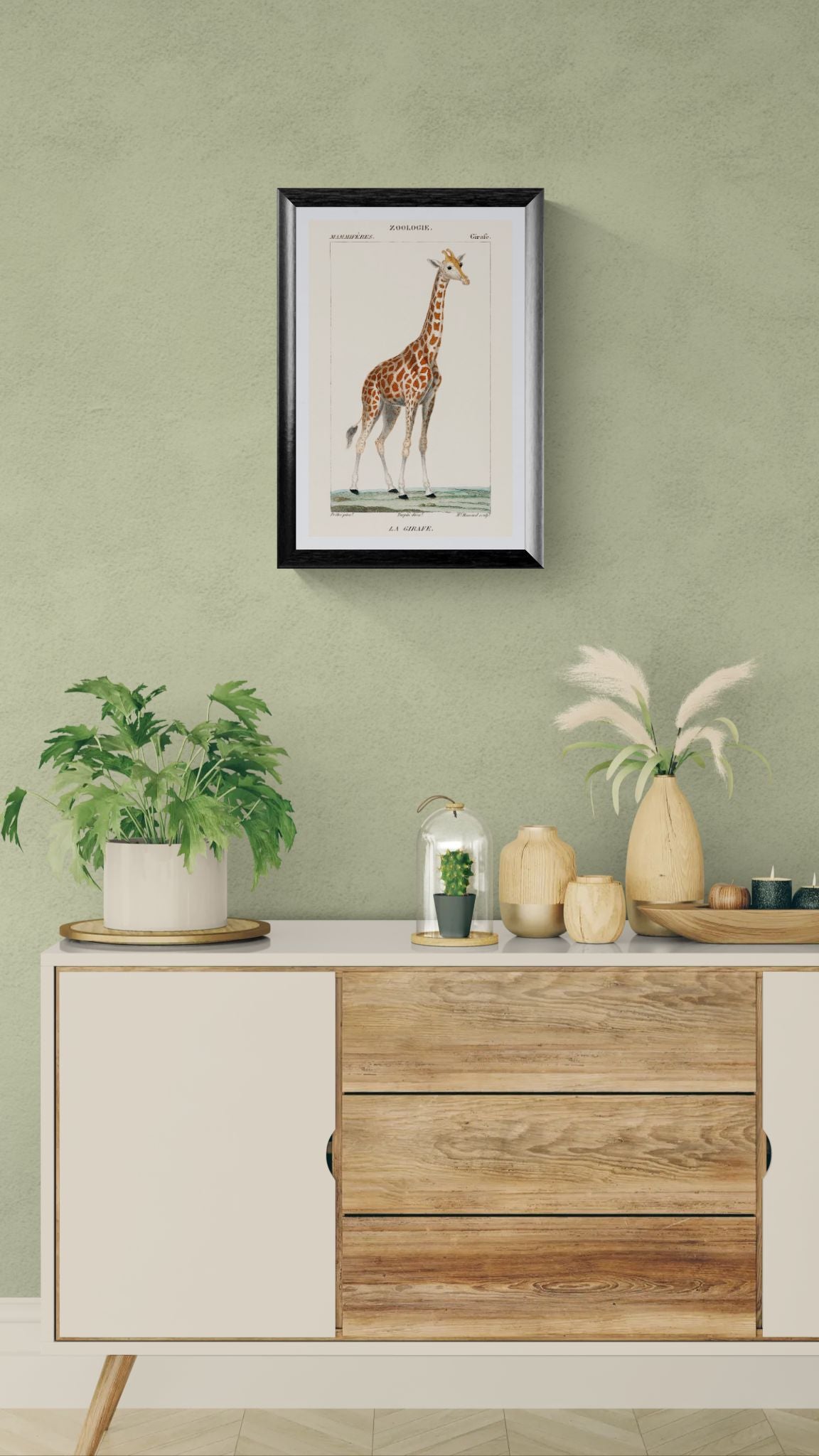 Framed giraffe print on a green wall above a wooden cabinet with decorative items.