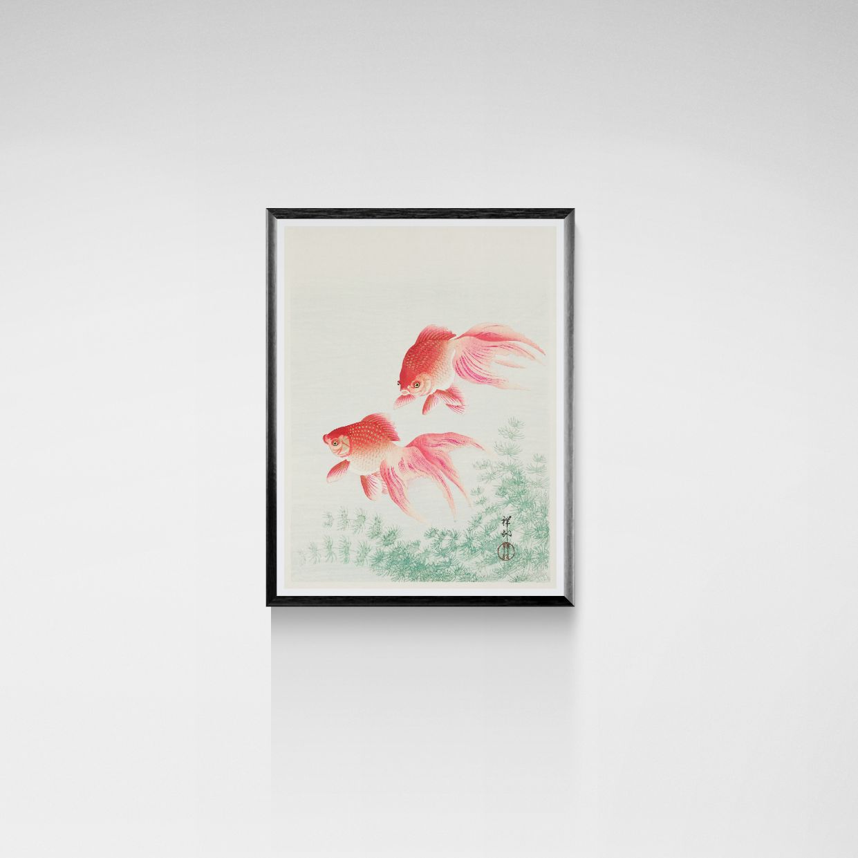 Framed artwork of two red fish on a light background
