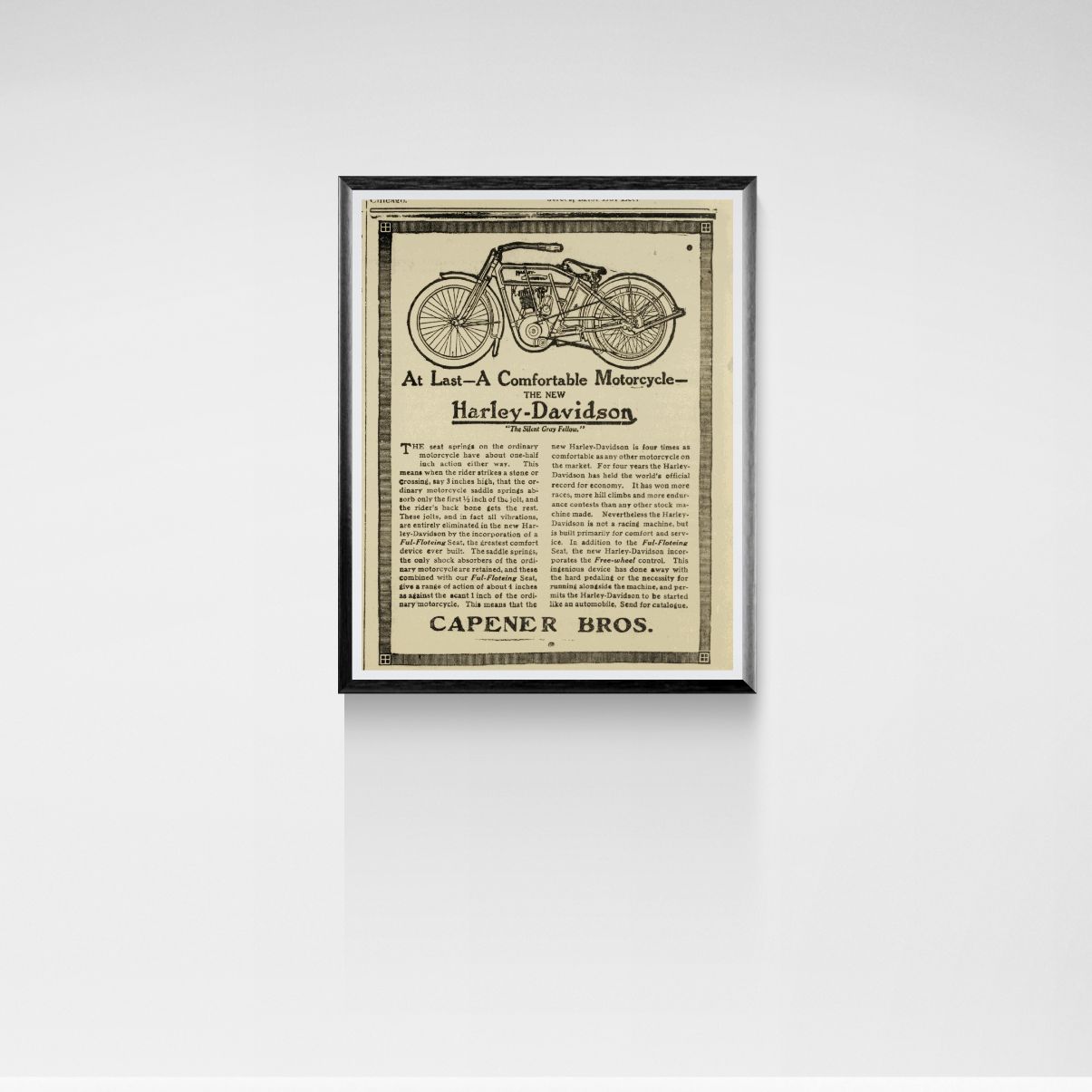 Framed vintage-style advertisement for a motorcycle on a white wall