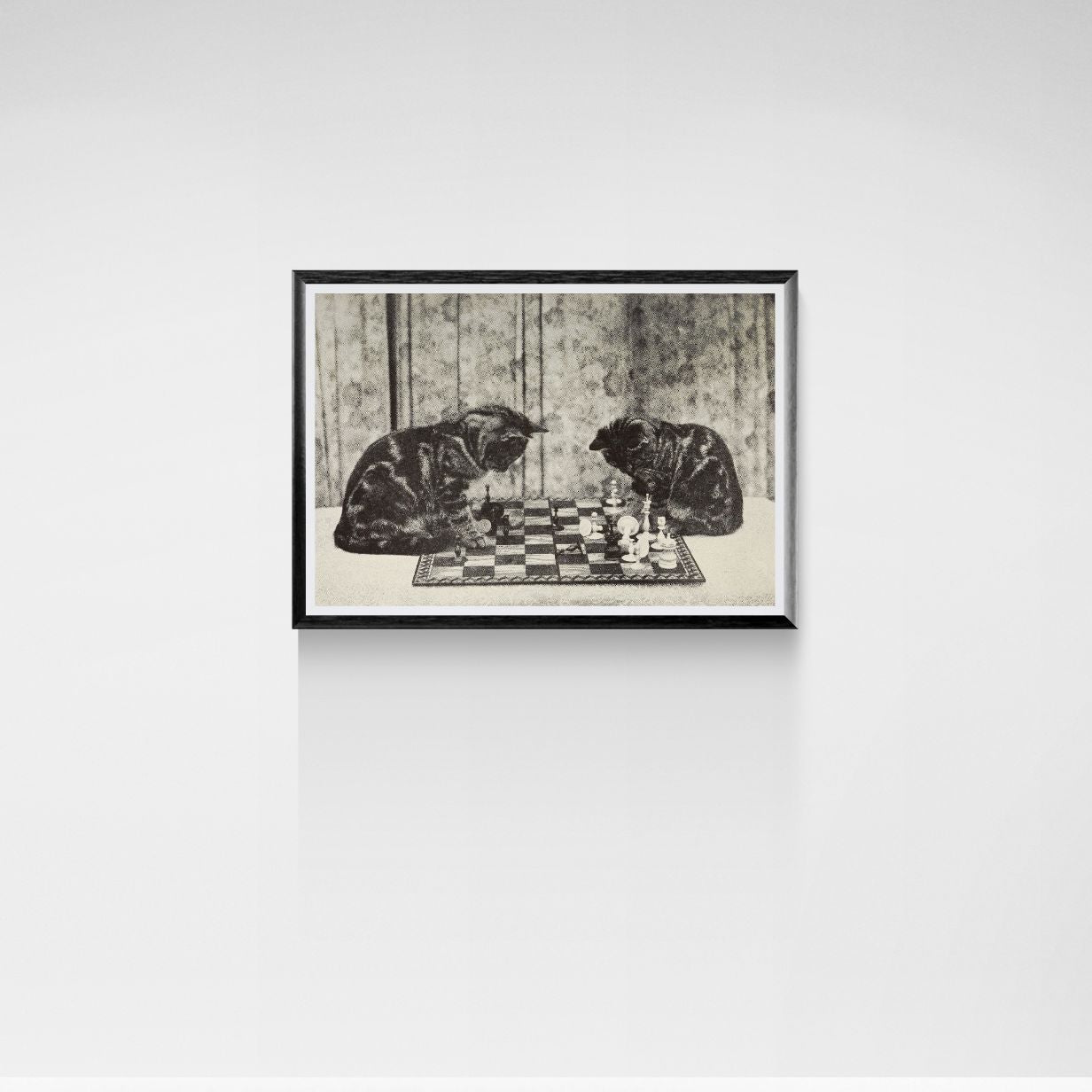 Framed artwork of two cats playing chess on a white wall