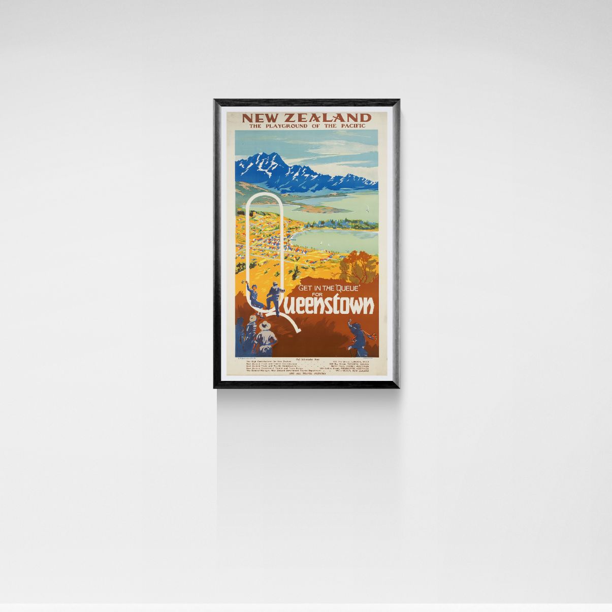 Framed travel poster for New Zealand, featuring Queenstown, on a white wall.