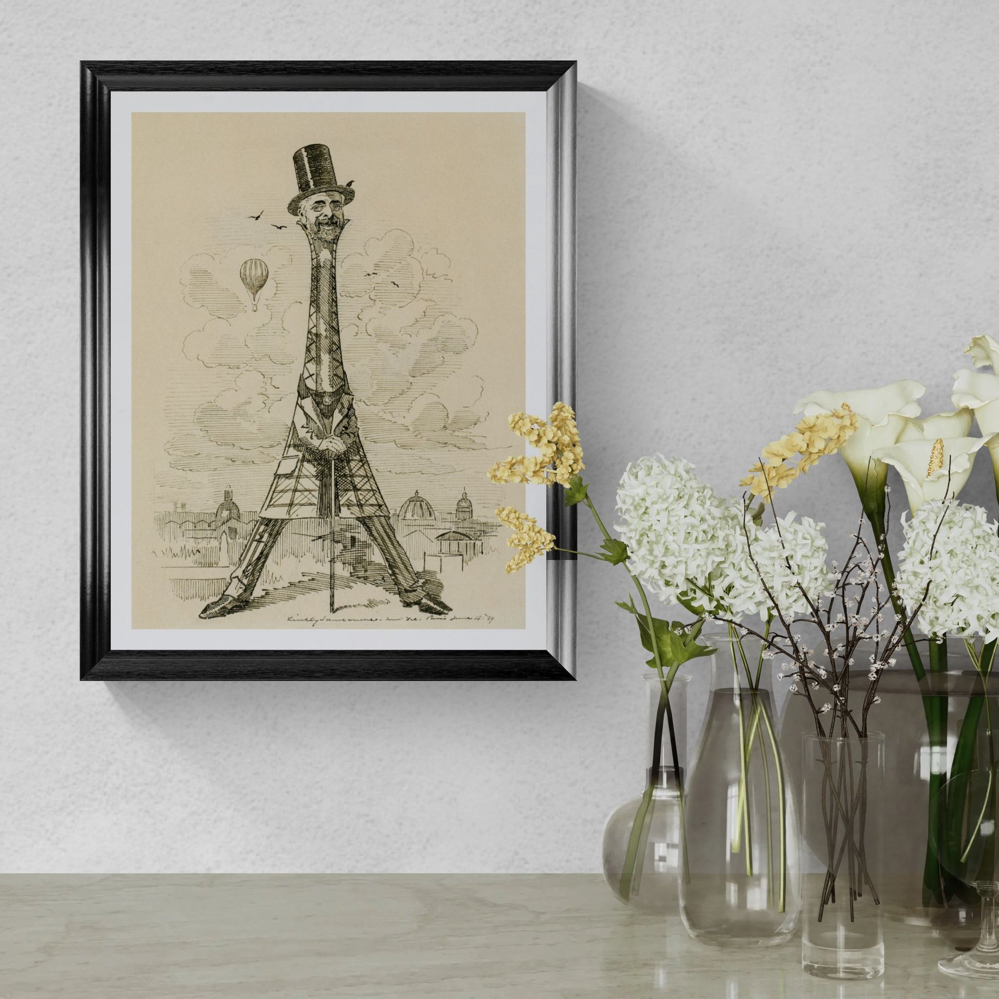 Framed artwork of a giraffe-like structure with a top hat on a wall next to vases with flowers.